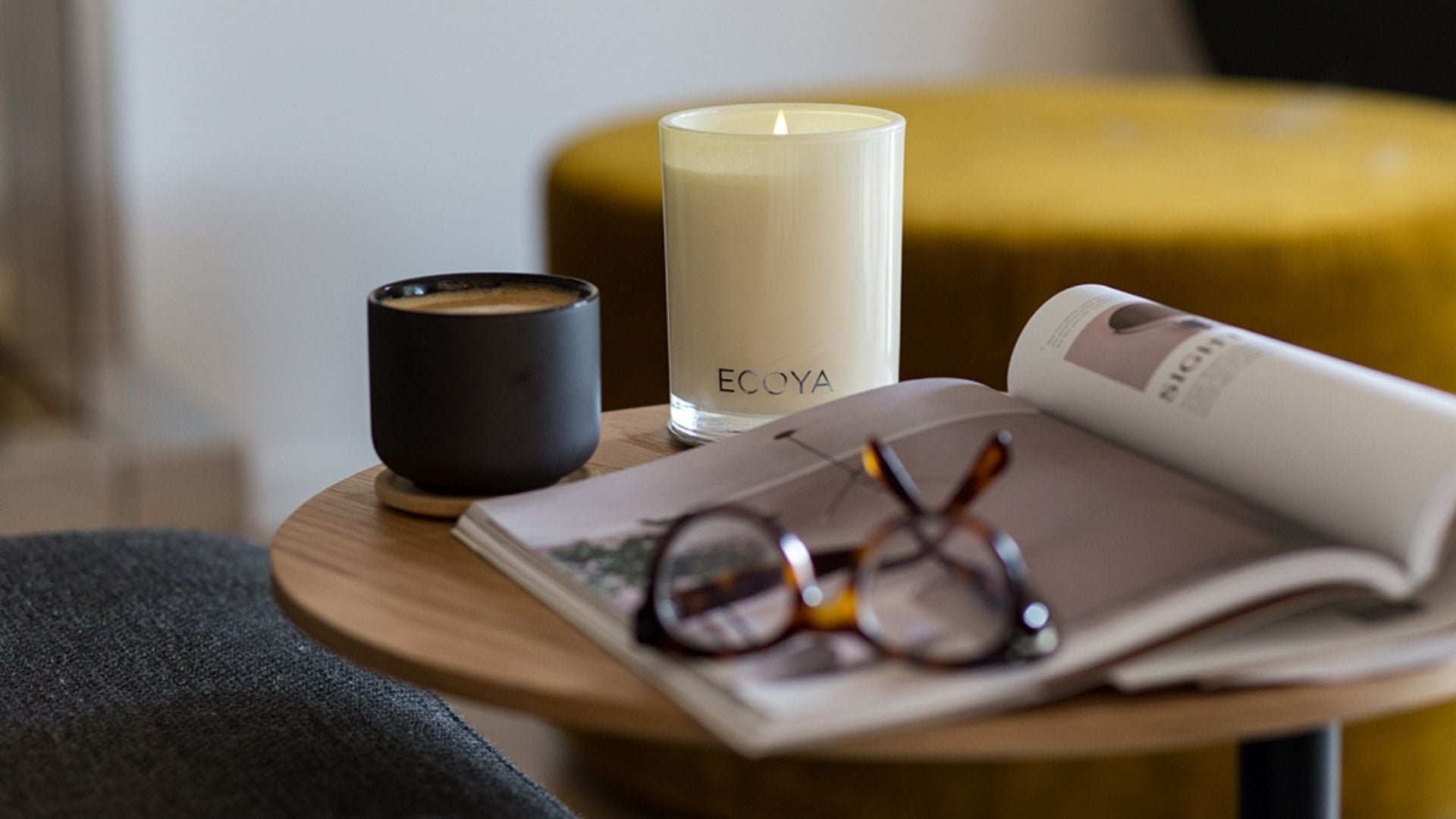 Ecoya candles, a magazine and glasses on a coffee table in the living room