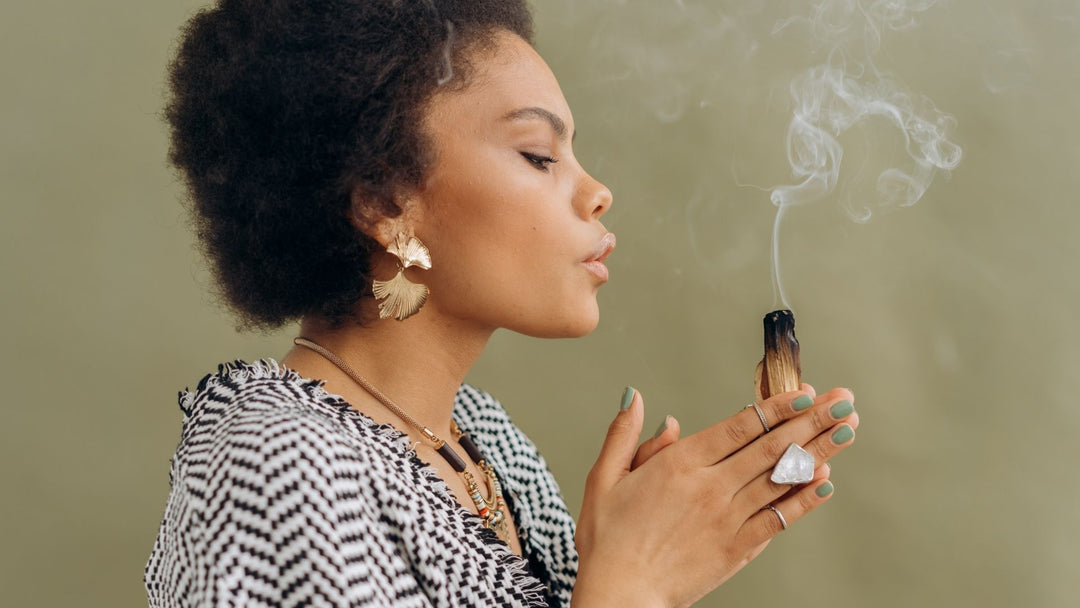 Woman blowing out a burning Palo Santo stick