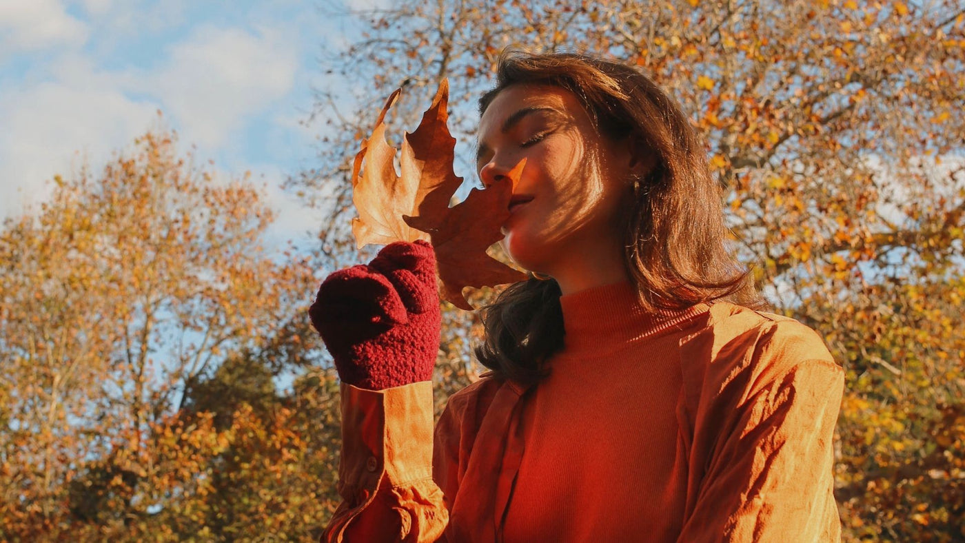 Woman smelling a maple leaf for an autumn fragrance
