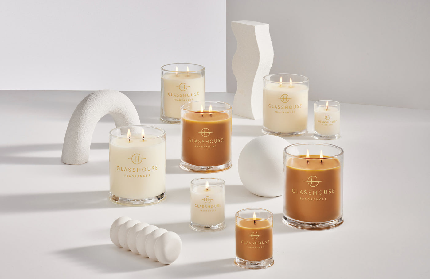 Four different varieties of scented candles on a pale pink background