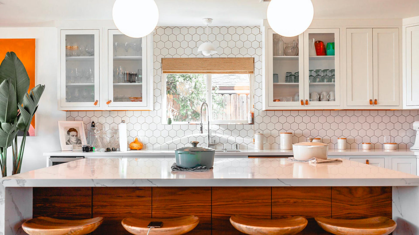 A bright white, tiled kitchen with a casserole dish on the bench top