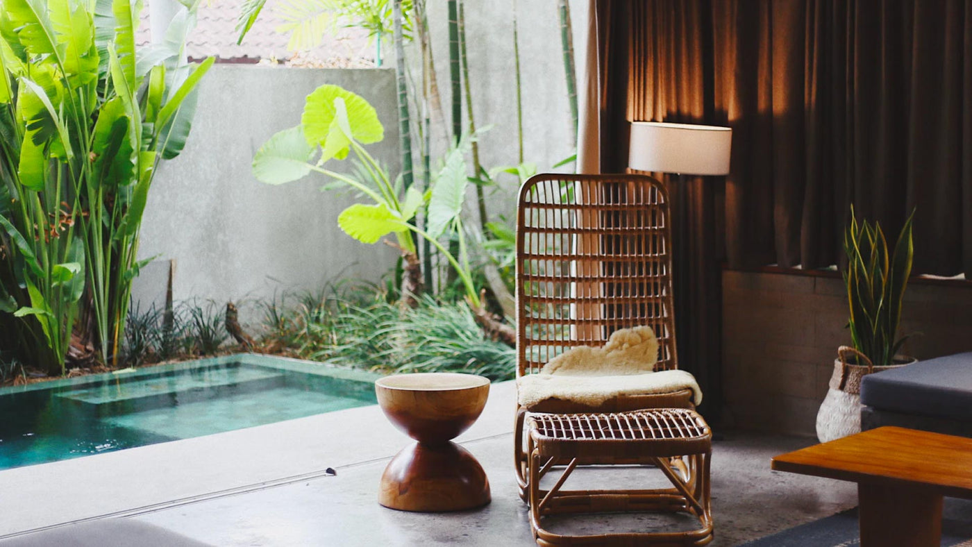 A tranquil outdoor setting with plants, a wicker chair and a pool