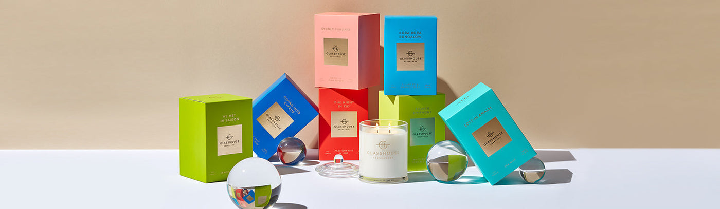A stacked collection of Glasshouse Fragrances candles in bright coloured boxes