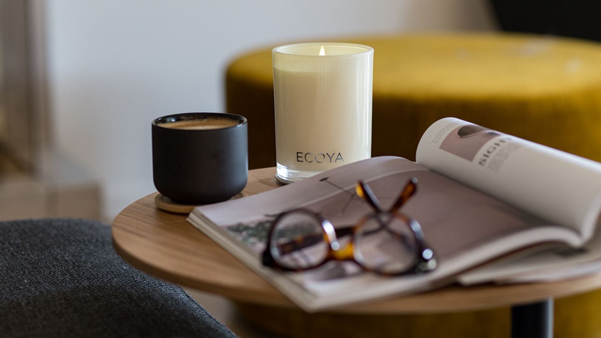 Ecoya candles, a magazine and glasses on a coffee table in the living room