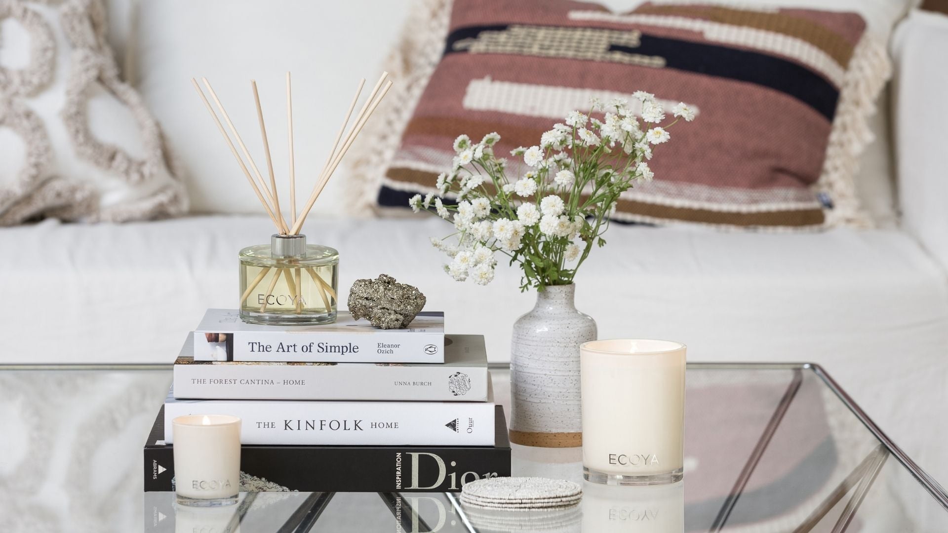 Ecoya living room diffuser on a stack of books on a glass coffee table